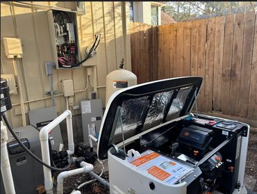 Open generator with connected pipes and electrical panel outdoors.