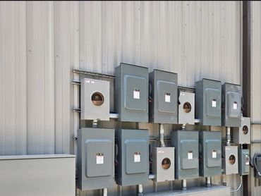 Multiple electrical panels mounted on a building exterior wall.