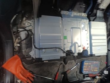 Car battery with tools and gloves.