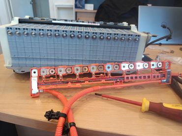 Battery pack with orange wiring on a desk.