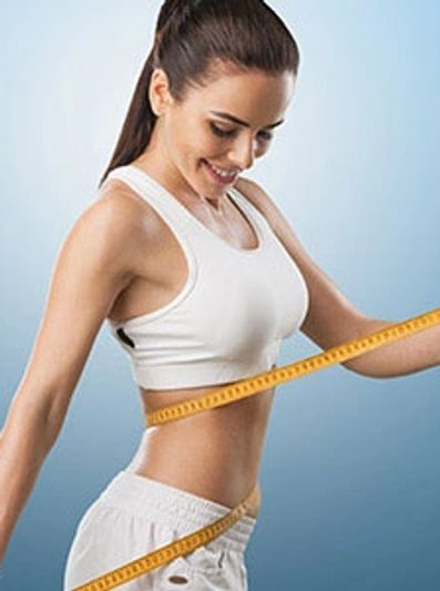 Woman measuring her waist with a tape measure, smiling.