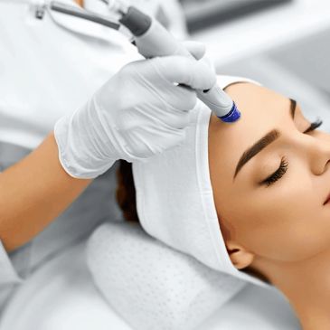 Woman receiving facial treatment with a device.