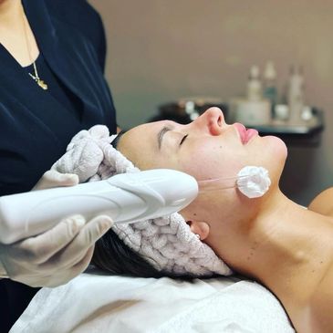 Woman receiving facial treatment with a device on her cheek.