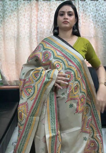 Woman wearing a colorful traditional saree with floral designs and large earrings.