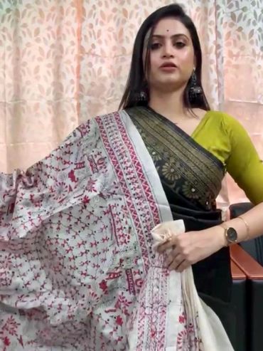 Woman showcasing a traditional printed saree with intricate red and black designs.