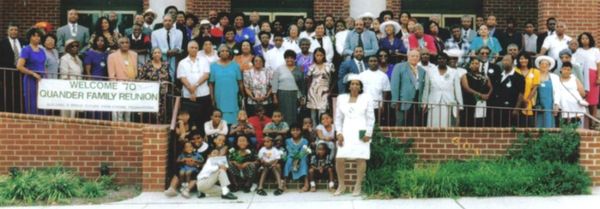 A large group of Quander family members gathering for the 70th reunion in front of a brick building