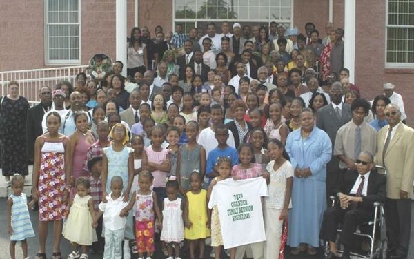 A group of Quander family members standing in front of a brick building