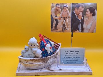 A decorative boat holds keepsakes with photos and a message on memories.