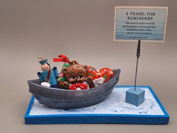A decorative boat filled with keepsakes like a teddy bear and toy soldier.