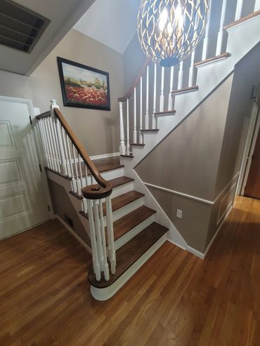Wooden staircase with white railings in a well-lit home interior.