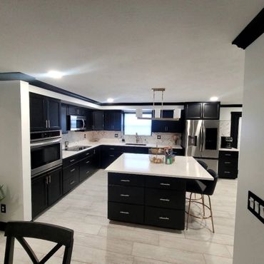 Modern kitchen with black cabinets and white countertops.