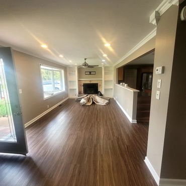 Empty living room with hardwood floors and a ceiling fan.