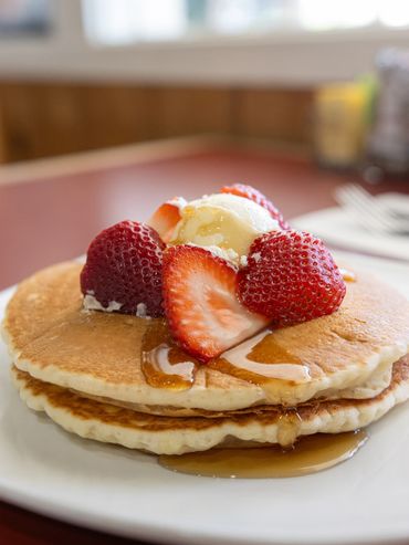 Two pancake stack with strawberries, butter and syrup