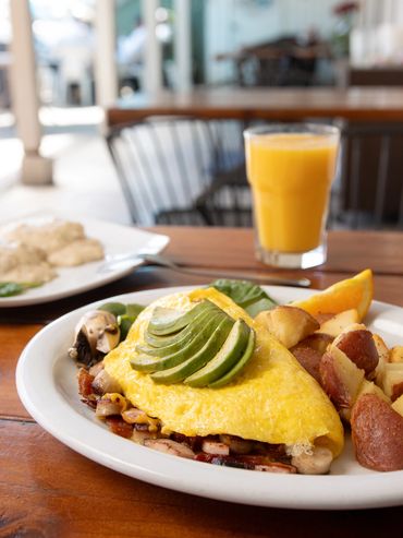 Meat lovers omelette with country potatoes. Biscuits and gravy and orange juice in the background.