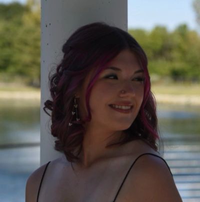 Young woman smiling with pink highlights in her hair.