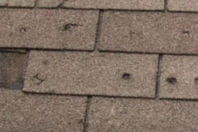 Close-up of storm-related roof damage on asphalt shingles