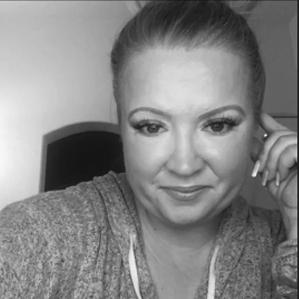 Black and white close-up portrait of a smiling woman in casual wear.