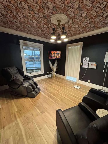 Modern room with floral ceiling, dark walls, comfortable chairs, and wooden floor.