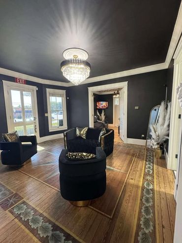 Elegant living room with dark walls, wooden floor, and crystal chandelier.