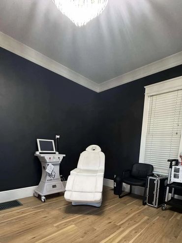 A modern aesthetic treatment room with a white chair and medical equipment.