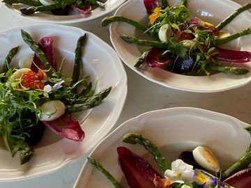 Plates of gourmet salad with asparagus, greens, and edible flowers.
