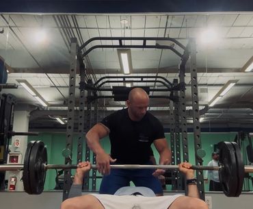 Male strength training with barbell bench press to build muscle and stay strong at Top Shape Charles