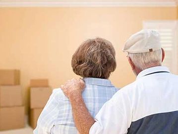 Senior couple in new home looking at moving boxes