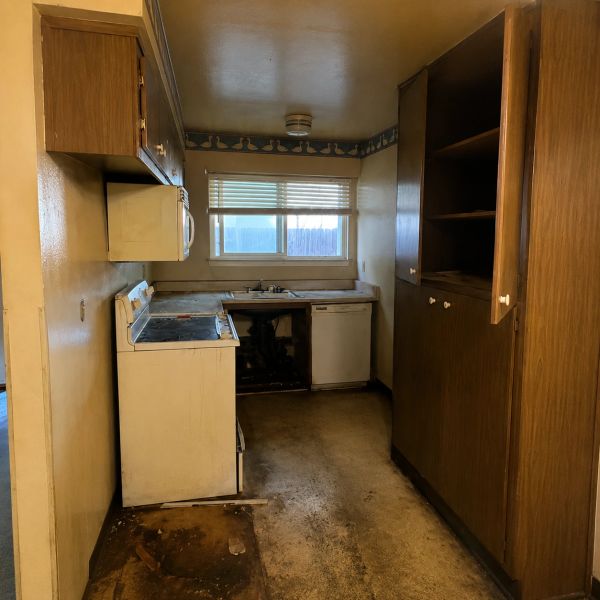 Before photo of Fremont kitchen remodel showing original dark wood cabinets, aging appliances, damag