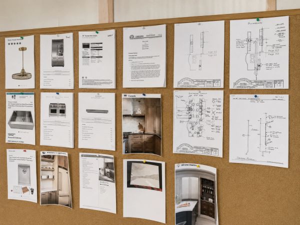 Remodeling project planning board featuring kitchen design drawings, appliance selections, cabinet s