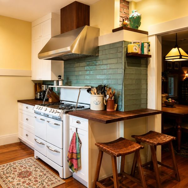Historic kitchen remodel featuring a restored antique range, handmade green tile backsplash, dark wa