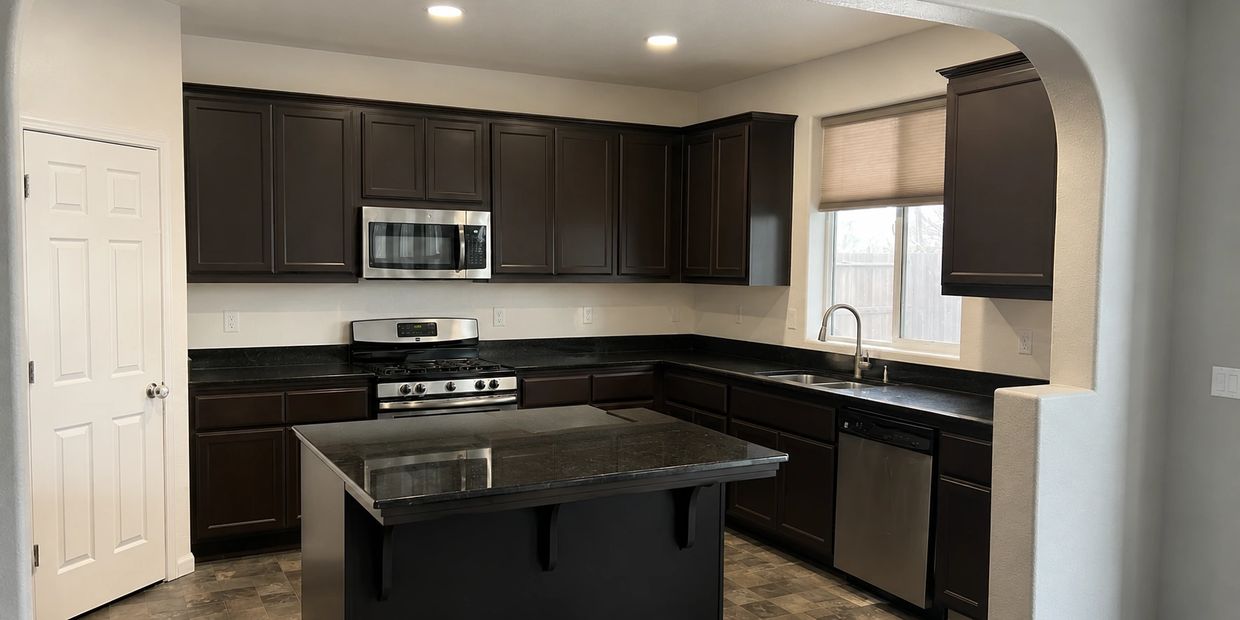 Kitchen before remodel with dark island, stove area, and original cabinet finishes