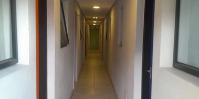 Narrow corridor with tiled floor and multiple doors on both sides.