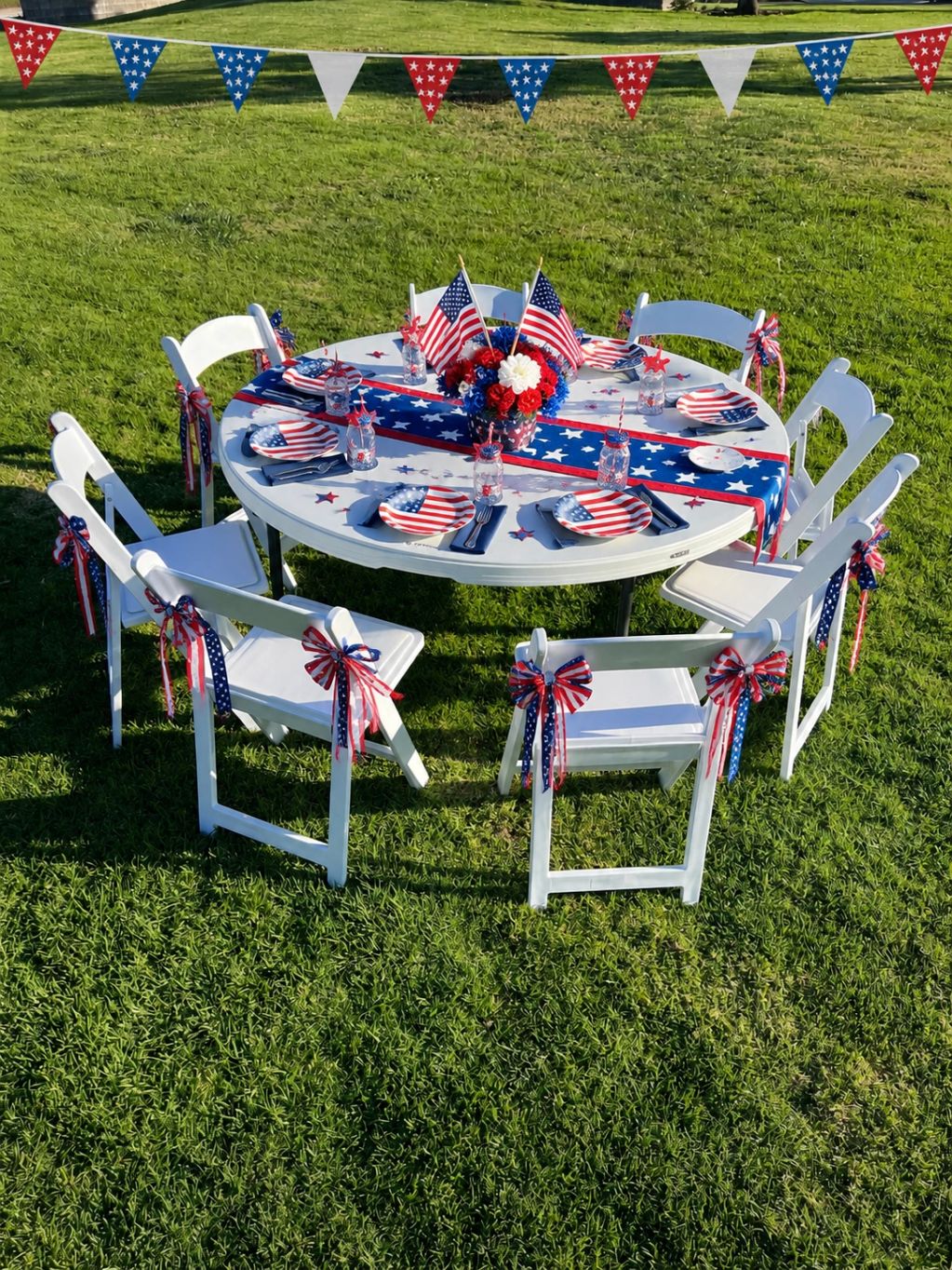 Outdoor table set decorated with American flags and patriotic colors for a celebration.