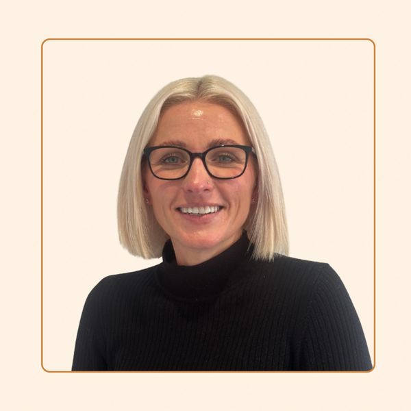 Smiling woman with glasses and blonde hair.