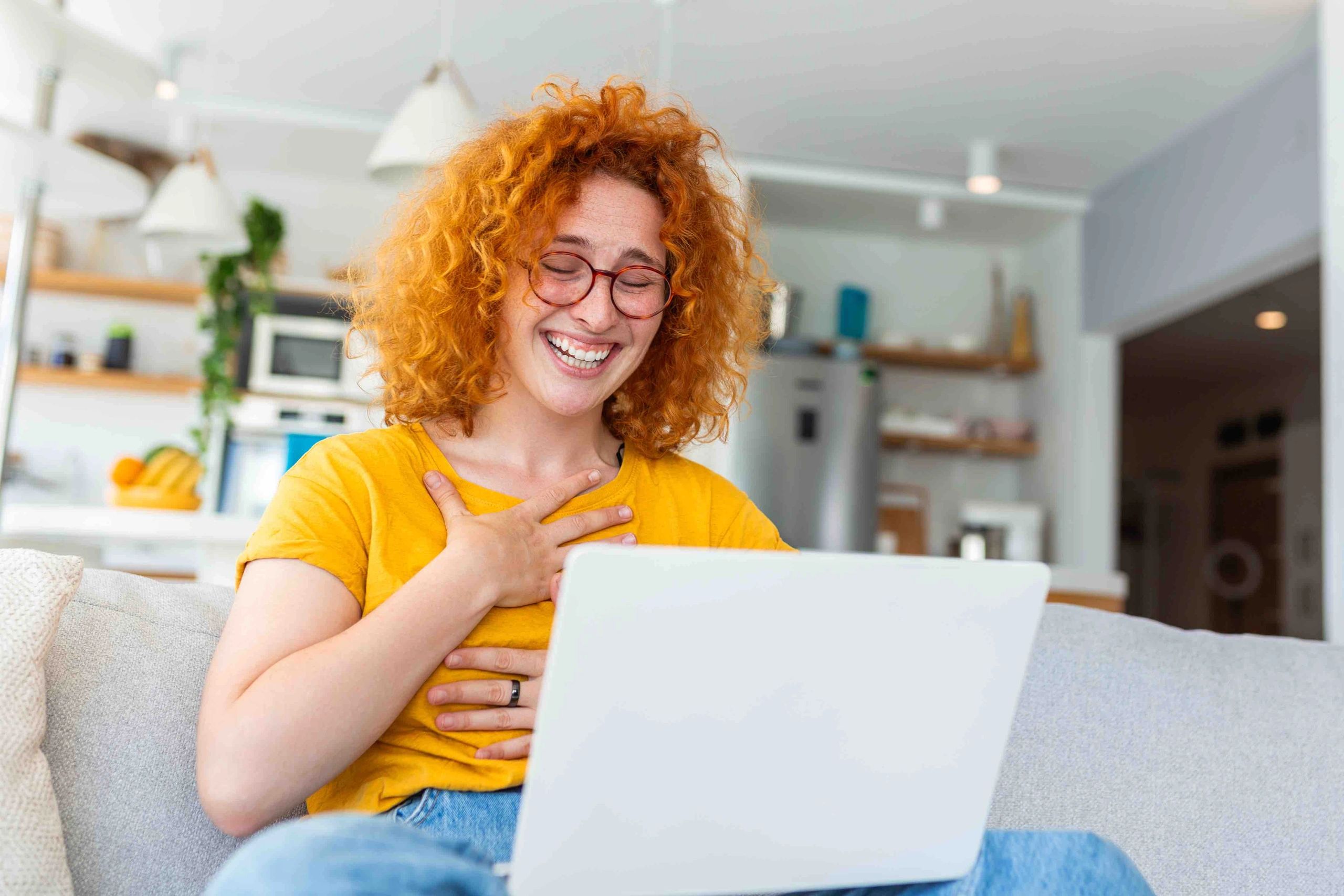 An educator on a video call on her computer talking and laughing with other teachers