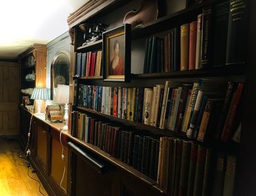 A cozy room with shelves of books, a portrait, and soft-lit lamps.