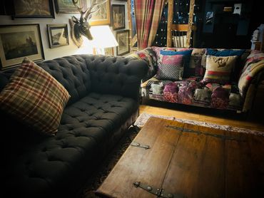 Cozy living room with patterned and dark sofas illuminated by a lamp.