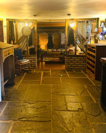 Cozy rustic living room with stone floor and brick fireplace.