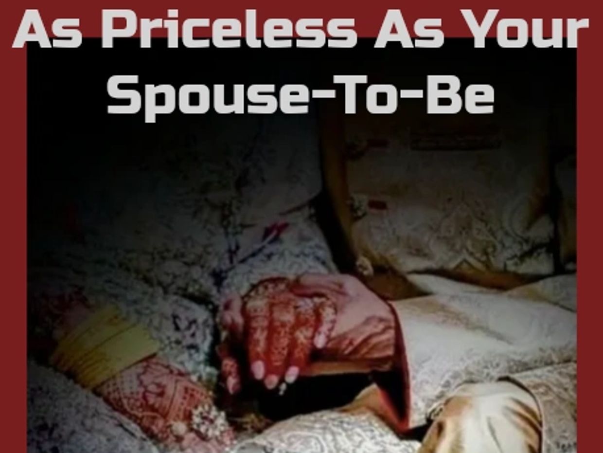 A photo of a newlywed couple sitting together with hands embraced, their reflection visible below.
