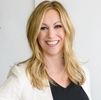 Smiling blonde woman in business attire with a white blazer and black top.