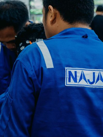 Person wearing a blue shirt with NAJAH logo on back.