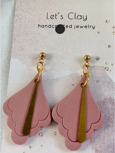 Pink handcrafted clay earrings with gold accents on a branded card.