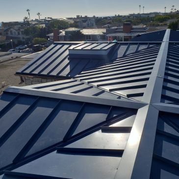 Shiny black metal roof with geometric design under clear sky.