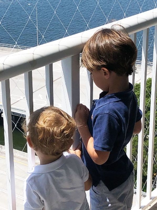Two boys looking over a balcony by the water.