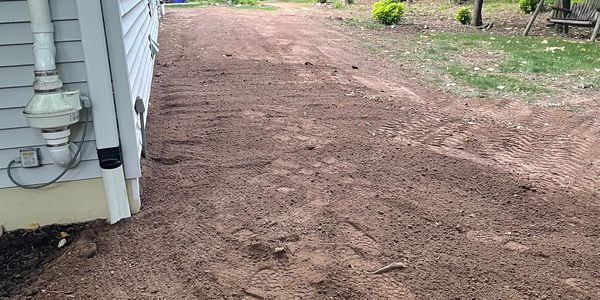 Freshly graded dirt path beside a house.