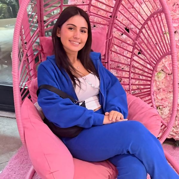Young woman sitting on a pink cushioned swing chair.