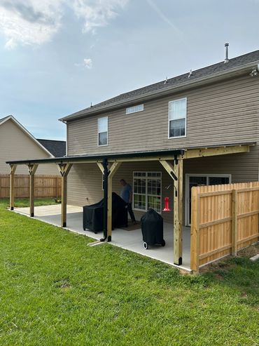 A backyard patio with a covered wooden pergola and grills.