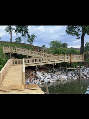 A wooden dock ramp leading from water to a grassy hill.