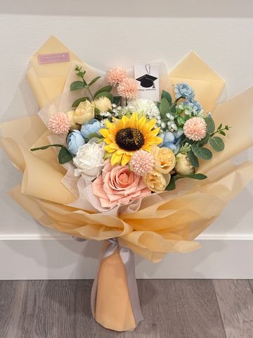 Elegant bouquet with sunflower, pastel roses, and soft yellow wrapping.