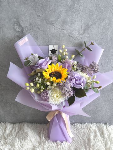 Elegant bouquet with sunflower and pastel purple flowers wrapped in lavender paper.